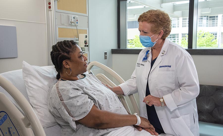 Female patient in hospital bed speaking to her Beaumont doctor