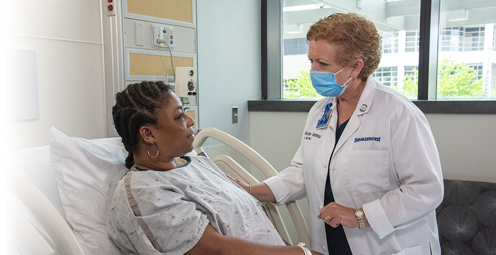 Female patient in hospital bed speaking to her Beaumont doctor