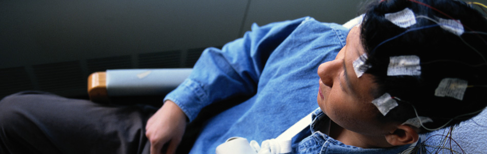 Male patient sitting in chair with epilepsy monitoring equipment attached to head