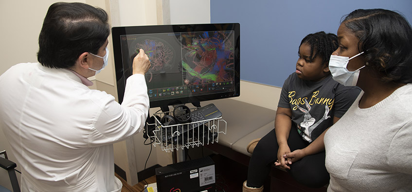 Doctor discusses surgical theater with child patient and parent