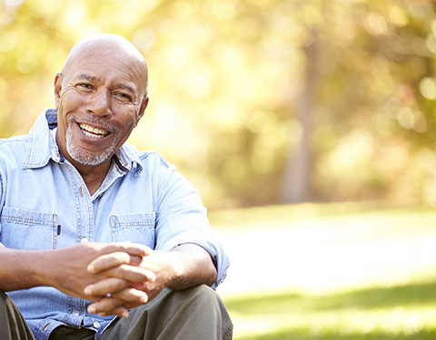 Senior male smiling and sitting outdoors