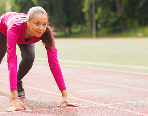 Strong young woman running on outdoor track