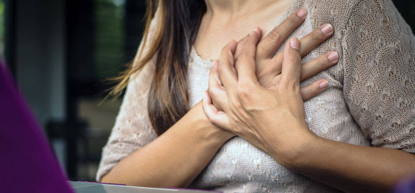 Woman experiencing breast pain while working at desk